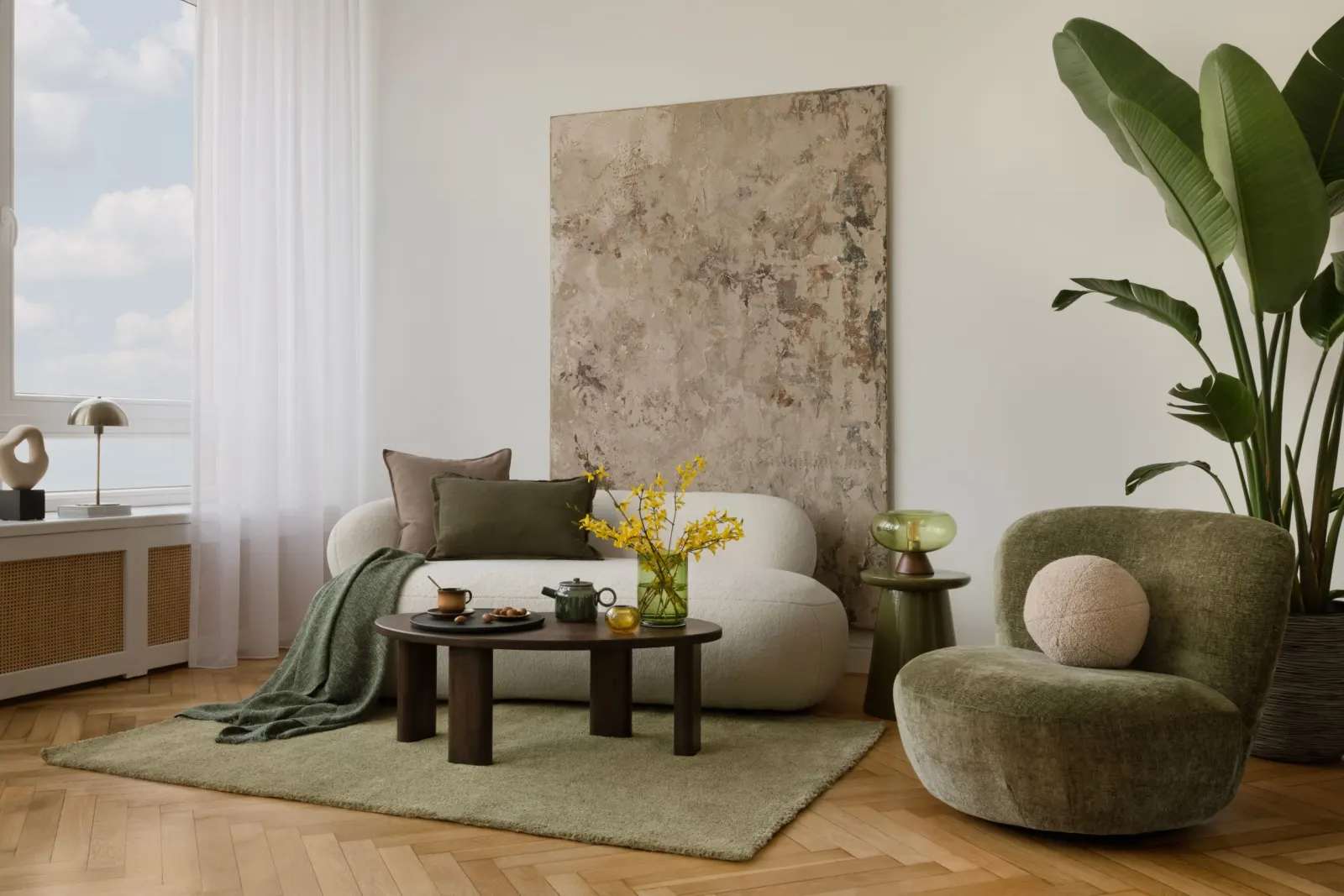 Salon lumineux avec fauteuil vert, canapé blanc, table basse en bois et grande plante verte